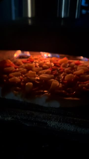 Pizza roasting beside a live flame in Giani’s oven
